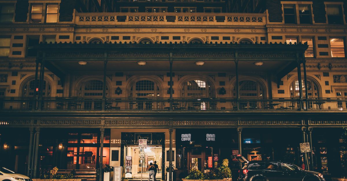 A beautifully illuminated historic building facade captured at night on a street in Houston, Texas.